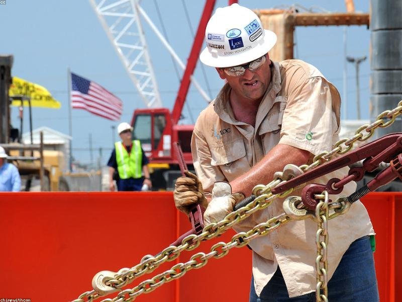 Construction worker in hard hat rigging heavy equipment on a foundation site