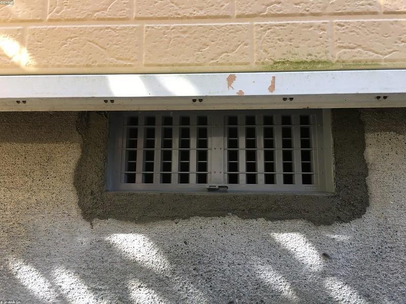 Foundation wall with vent opening showing concrete repair work