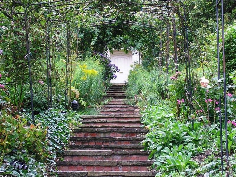Brick masonry steps leading through a garden arbor to a door — finished stair and retaining work